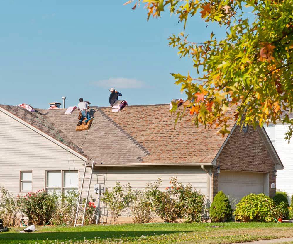 Roofers repairing the roof of a house in the suburbs.