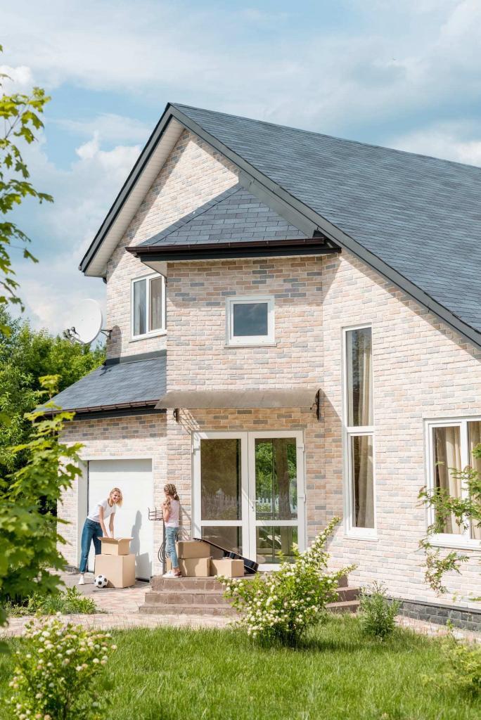 young mother and daughter outside lovely home with cardboard boxes