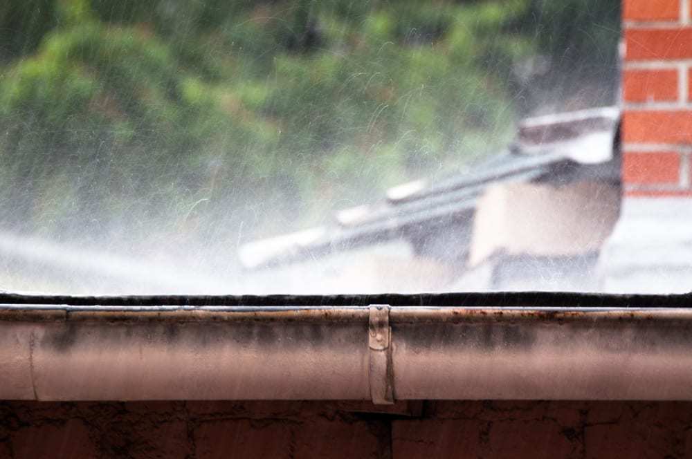 Heavy rain pounding the edge of a roof, gutters
