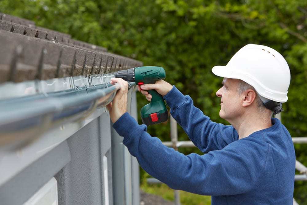 Man Replacing Gutters on Exterior of House