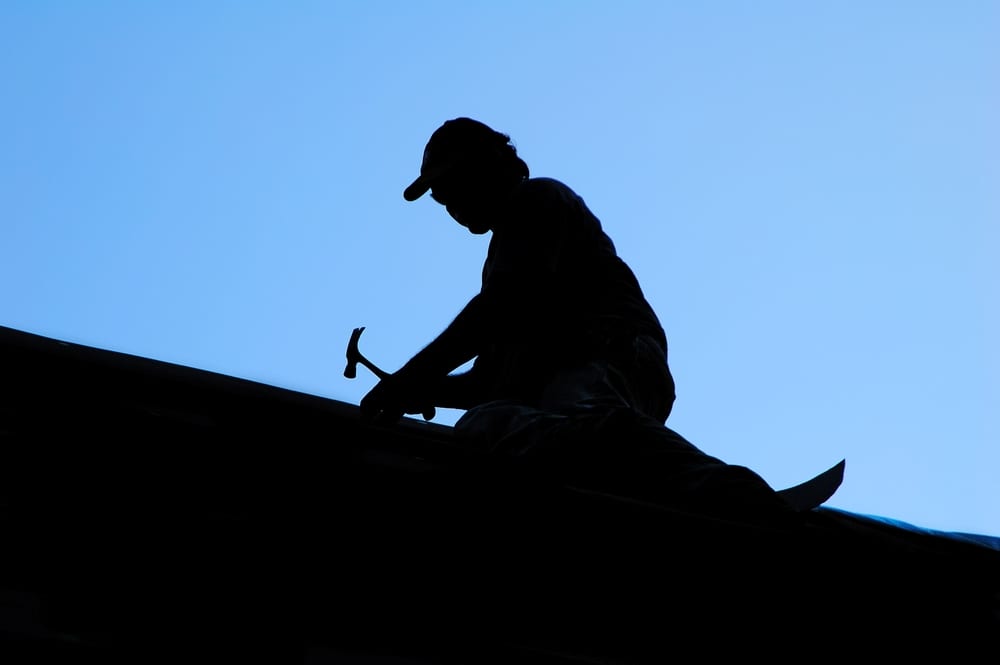 Silhouette of roofer, blue sky