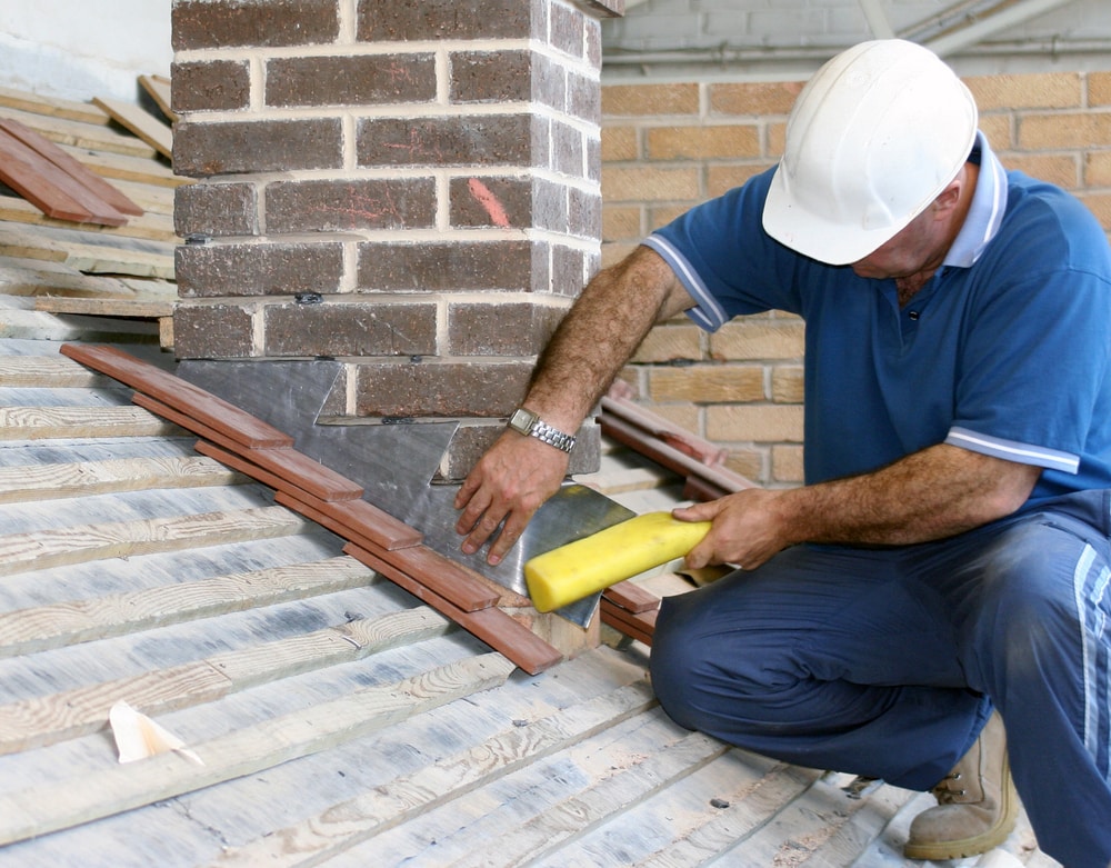 Roofer adding flashing around chimney