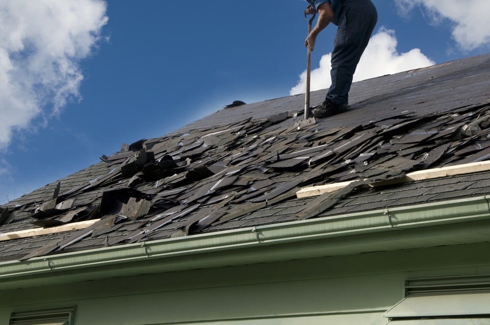 Roofer removing old shingles from roof
