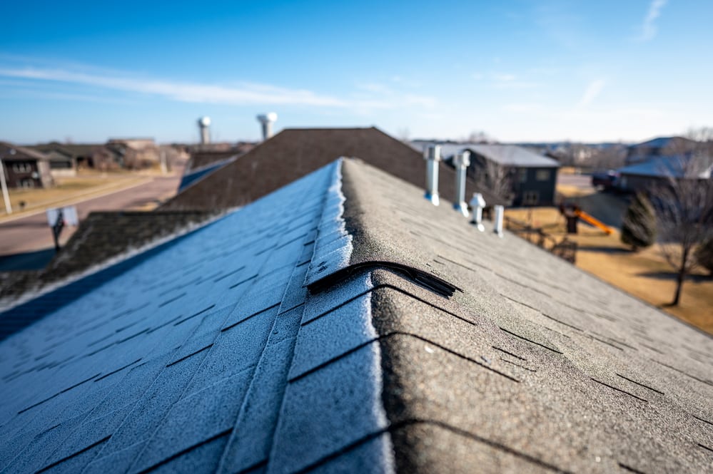 Frost line on a shingled roof as the sun rises and melts it