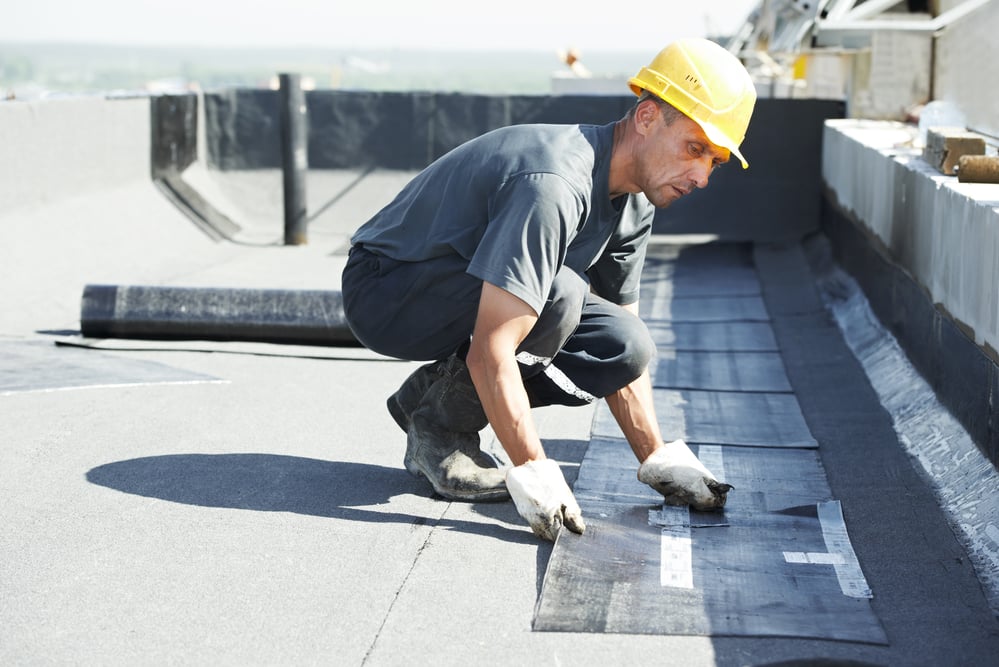 Roofer laying bitumen roofing on commercial roof