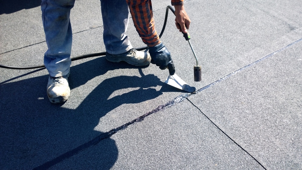 roofer preparing part of bitumen roofing felt roll