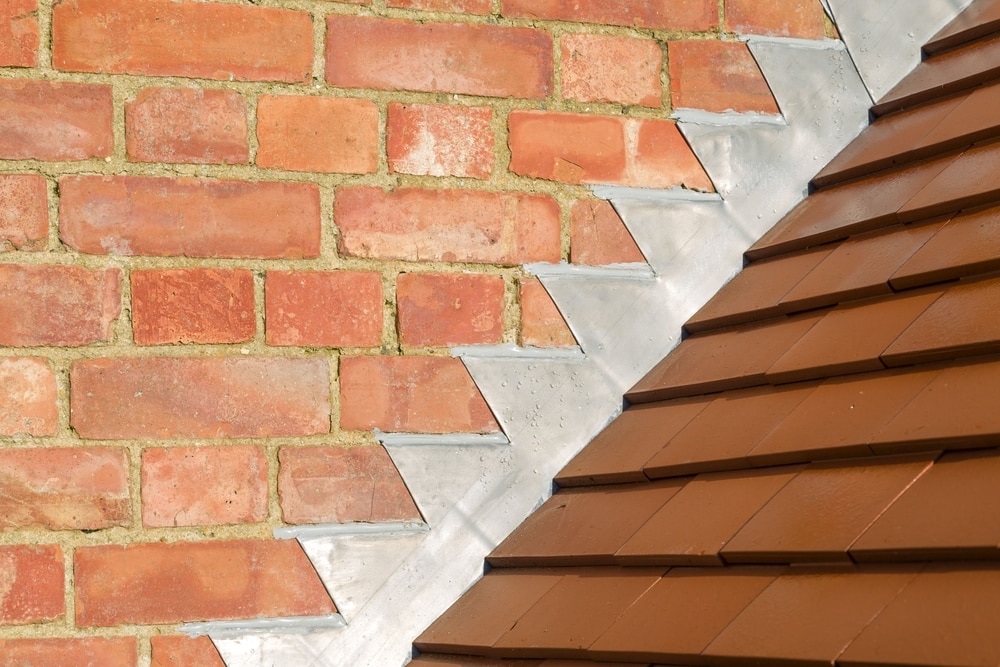 Closeup of clay tile roof, lead flashing, and brick chimney