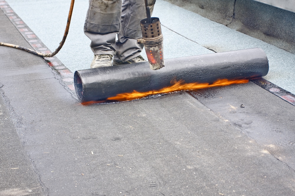 Roofer welding tar paper to roof