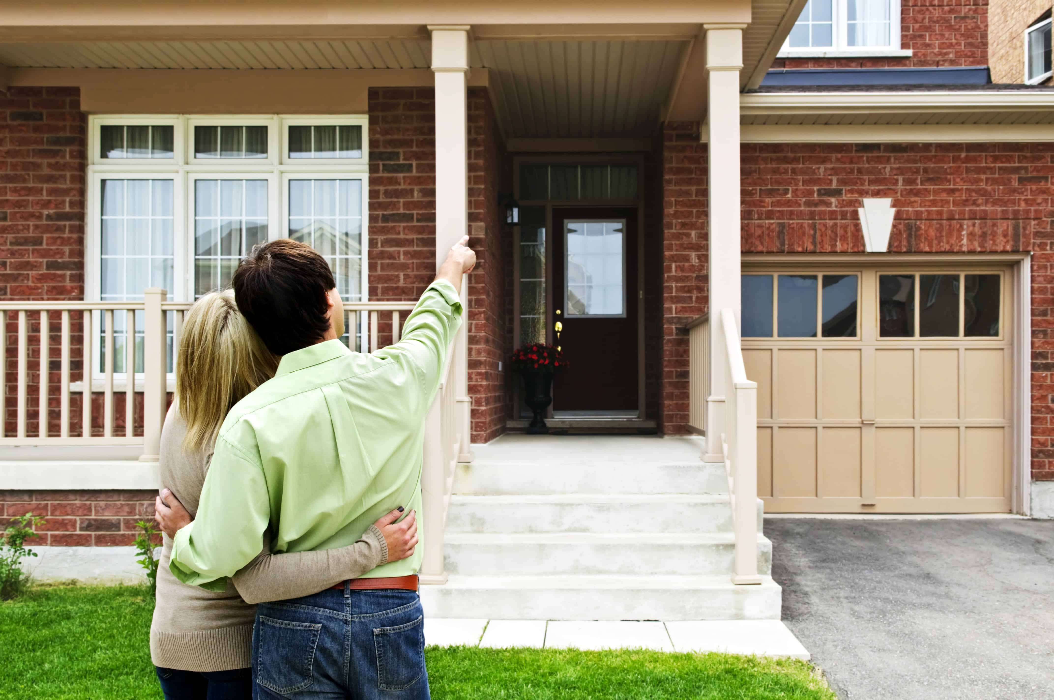 Young couple looking at home, man pointing at roof