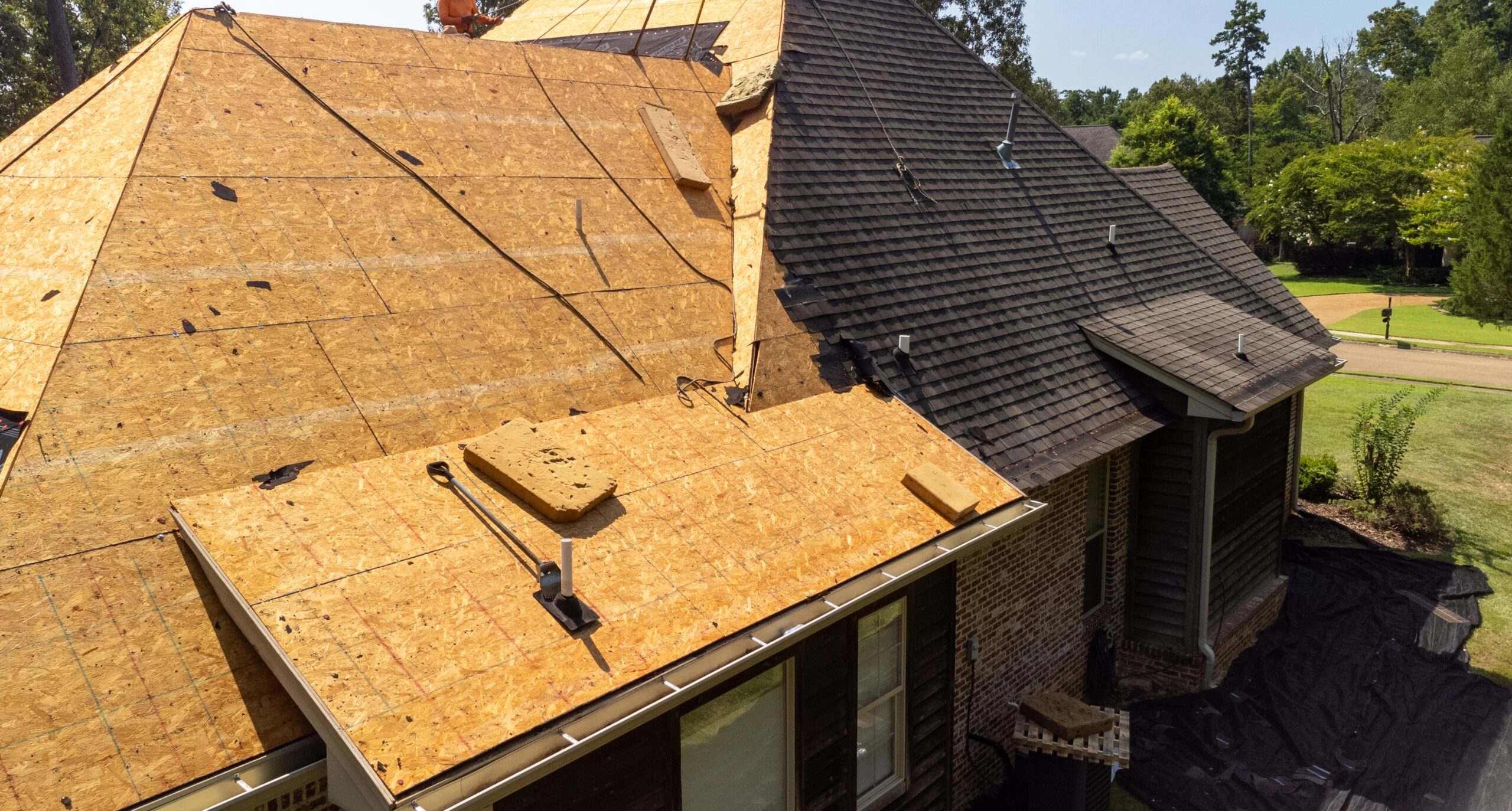 Home roof, decking exposed, new shingles being installed